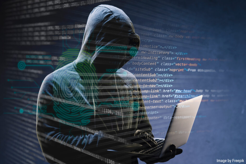 hooded cybersecurity criminal using laptop