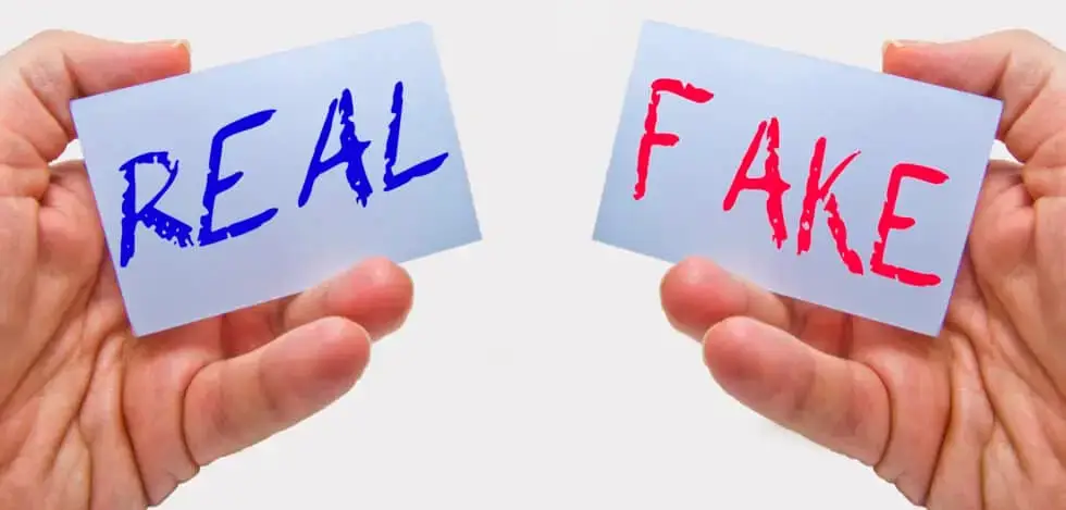 left hand holding card that reads real and right hand holding card that reads fake