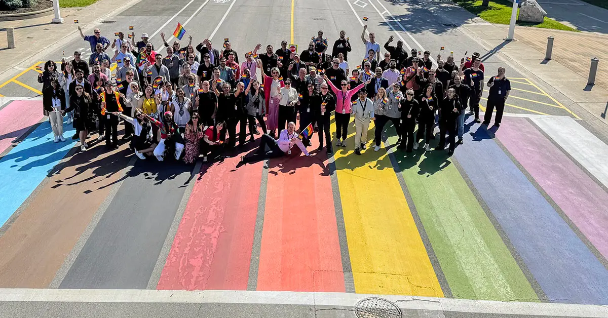 group poses on large chalkpainted pride flag