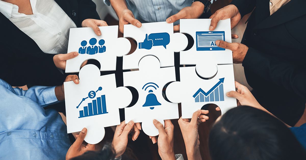 A diverse team collaboratively assembles puzzle pieces, each representing key business concepts like growth, communication, and strategy for successful teamwork.